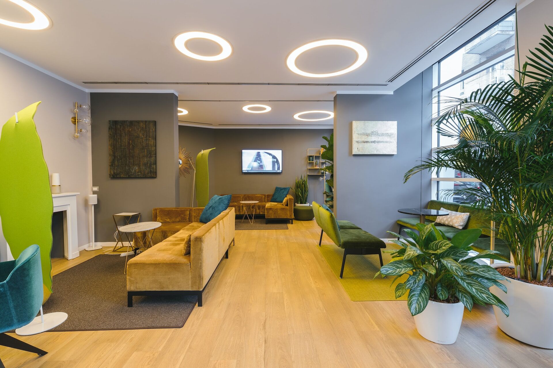 Ein modernes Büro mit stilvollem Holzboden, eleganten grauen Wänden, einem großen Fenster für viel Tageslicht und einem gemütlichen Kamin auf der rechten Seite. Die Möbel sind geschmackvoll arrangiert und schaffen eine inspirierende Arbeitsumgebung. | Ruiz Gebäudereinigung